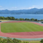 湖と山を背景にした陸上競技場の全景
