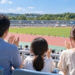 陸上競技場の地域の大会で拍手する家族の後ろ姿