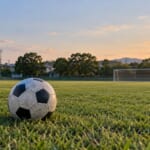 夕方のサッカーグラウンドと芝の上のボール