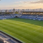 夕方のサッカースタジアムの全景。緑の芝と青い観客席