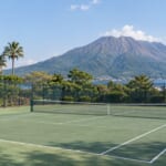 火山と南国の木を背景にしたテニスコート